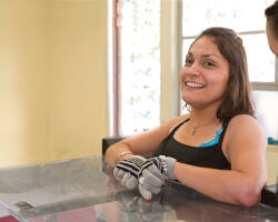 A young hispanic woman with cerebral palsy is helped into a standing desk