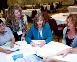 TCRC staff and stakeholders sit at a round event table discussing training