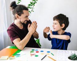 Happy boy with autism during therapy with school counselor, learning and having fun together