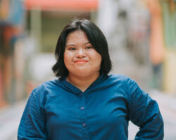 Asian women with down syndrome smiles at camera in a city setting